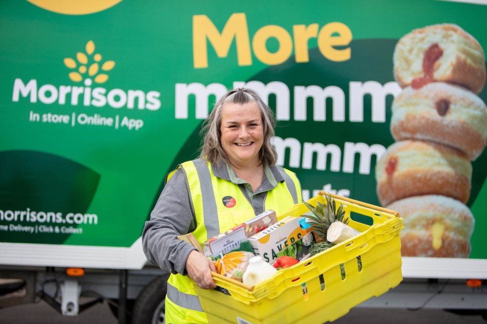 Delivery colleague holding a box of products in front of a delivery van