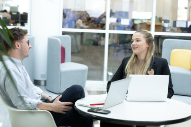 Two head office colleagues chatting over laptops